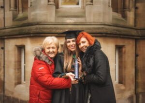 A graduate with her mother and grandmother holding a diploma on the Nottingham University campus during a photoshoot.