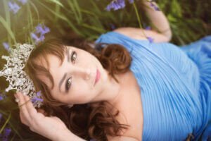 Empowering women photoshoot in Nottingham - Woman wearing crown and prom dress among bluebells.
