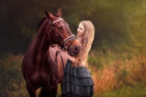 Woman gently holding her horse during a sunset equine photoshoot