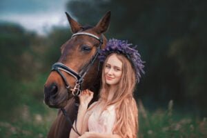 Young woman with a lavender crown posing with her horse during an equine photoshoot