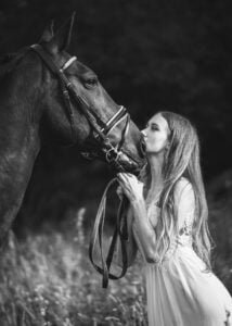 Equine photoshoot with young woman kissing her horse