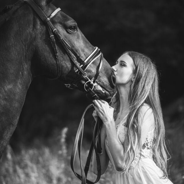 Equine photoshoot with young woman kissing her horse