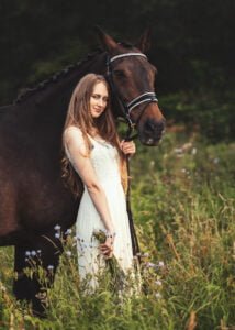 Woman standing in a meadow with her horse during an elegant equine photoshoot