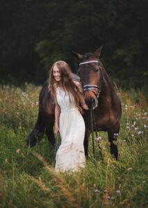 Young woman walking with her horse in a field during an equine photoshoot