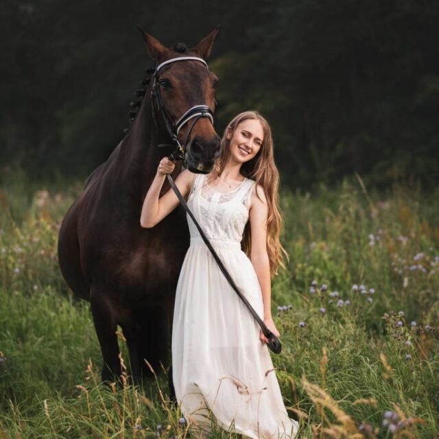 Smiling woman standing next to her horse during a horse photoshoot