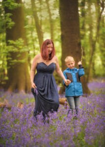Mother and son holding hands while walking through bluebell woods in Nottingham during a family photoshoot.