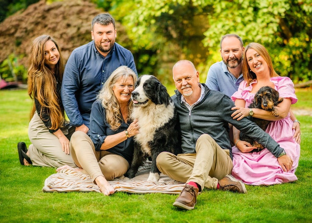A multi-generational family gathers in joyful unity with their cherished dogs in a Nottingham garden, showcasing the signature touch of a skilled Nottingham dog photographer.