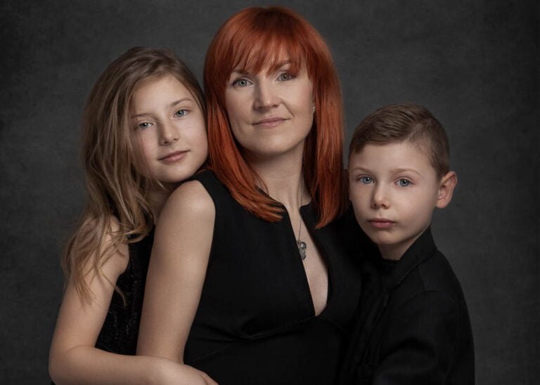 Mother with red hair poses with her daughter and son in a family portrait.
