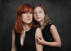 Mother and daughter in black outfits posing together during a studio photoshoot