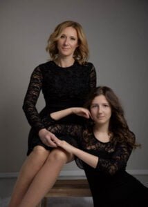 Mother and daughter in black dresses during a studio photoshoot, exuding elegance and grace