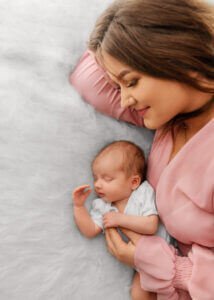 A heartwarming moment of a mother with her newborn daughter on a soft white fur bed throw.