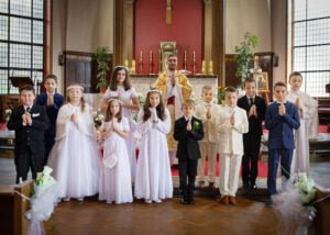 Group photo of children with a priest at the altar during a First Holy Communion ceremony.