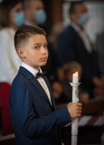 Boy holding a candle during his First Holy Communion ceremony in Nottingham.
