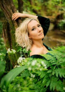 Woman in green dress leaning against a tree in a professional portrait.