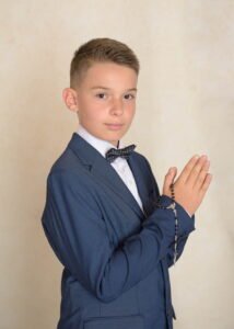 Boy in a blue suit holding a rosary during his First Holy Communion Photography session.