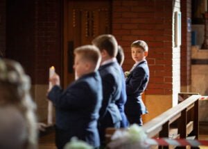 Boy in a navy suit in a church aisle during his First Holy Communion Photography session in Nottingham.