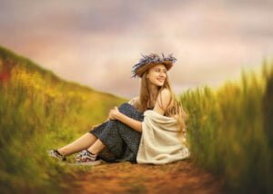 Professional portrait of a woman sitting in a sunset-lit field.