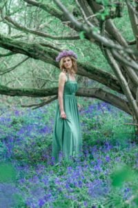 Professional portrait of a woman in green with purple flowers.