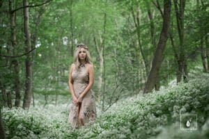 Professional portrait of a woman in a floral dress in enchanting woodland.