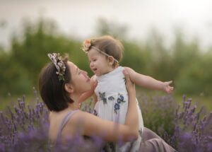 Mother lying in a lavender field with her baby, sharing a joyful and intimate connection captured through breastfeeding photography.