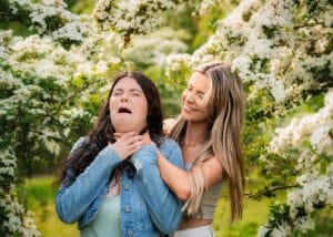 Two women in a playful pose with blossoming trees during a best friends photoshoot in Nottingham