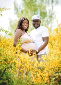 Expectant couple posing in a vibrant yellow flower field during their outdoor maternity photoshoot in Nottingham.