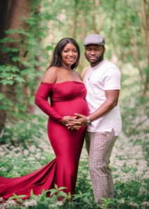 Expectant couple holding hands and cradling the baby bump during their outdoor maternity photoshoot in a Nottingham forest.