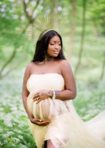 Radiant mother-to-be in a flowing cream gown and celestial headpiece during an outdoor maternity photoshoot in Nottingham forest.