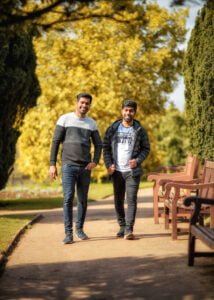 Two friends walking and chatting in a sunlit park during a friendship photoshoot in Nottinghamshire