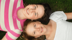 Two girls lying on grass and smiling during a creative friends photoshoot in Nottingham