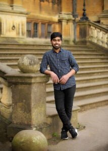 Man leaning on stone railing in front of historic Nottingham building during friends photoshoot