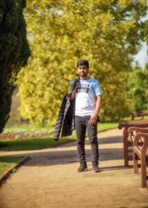 Man walking in sunlit Nottingham park with jacket over his shoulder during a friends photoshoot