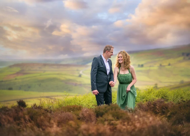 Smiling couple holding hands in the Peak District near Nottingham, with a picturesque sunset backdrop, celebrating couple photography.