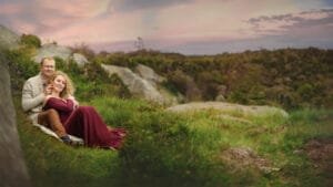 Couple seated in a grassy field during their Nottingham anniversary photography session at sunset