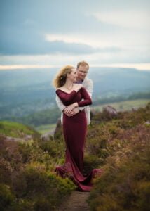 Romantic outdoor anniversary photography in Nottingham with a couple embracing on a hillside with a scenic view