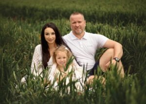 Family sitting together in a field during a baby bump photo shoot in Nottingham.