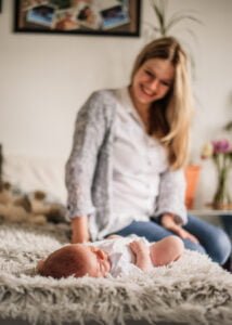 Newborn baby resting on mother’s lap during a lifestyle photography session at home in Nottingham.
