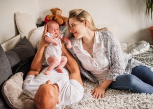 Family relaxing with their newborn baby on a bed during a lifestyle photoshoot at home in Nottingham.