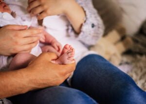 Close-up of a newborn baby’s tiny feet being held by parents during a lifestyle newborn photography session in Nottingham.