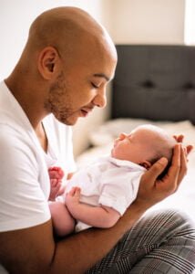 Father cradling newborn baby during a lifestyle newborn photography session at home in Nottingham.