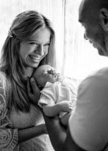 Black and white photo of parents smiling while holding their baby during a lifestyle newborn photoshoot in Nottingham.