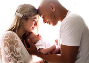 Parents smiling lovingly at their baby during a lifestyle newborn photography session in Eastwood, Nottingham.