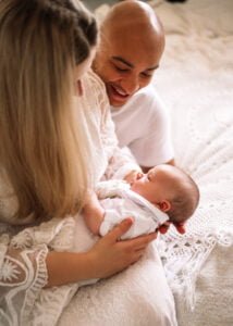 Family smiling at their newborn baby during a cozy and relaxed lifestyle newborn photography session in Nottingham.