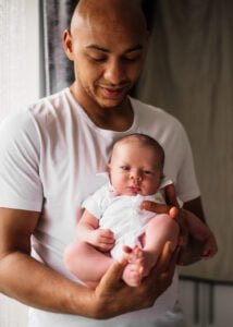 Father holding his newborn baby during a lifestyle newborn photography session at home in Nottingham.