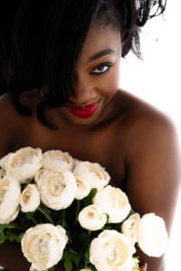 Intimate Joy at 40: A close-up of a woman's warm, inviting smile, her eyes sparkling above a bouquet of pristine white roses, symbolizing a celebration of life