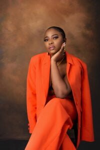 Woman in a bright orange suit sitting confidently during a studio birthday photoshoot in Nottingham.