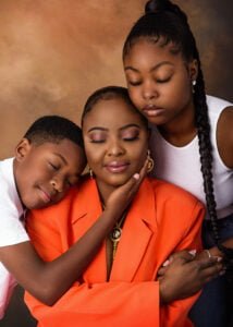 A mother in an orange suit hugging her two children during a heartwarming birthday photoshoot in Nottingham.
