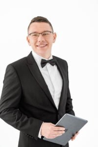 Male professional holding a tablet and smiling confidently during a professional business photoshoot with a clean white background.