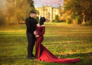 Expectant couple standing together in a field during a maternity photoshoot at sunset.