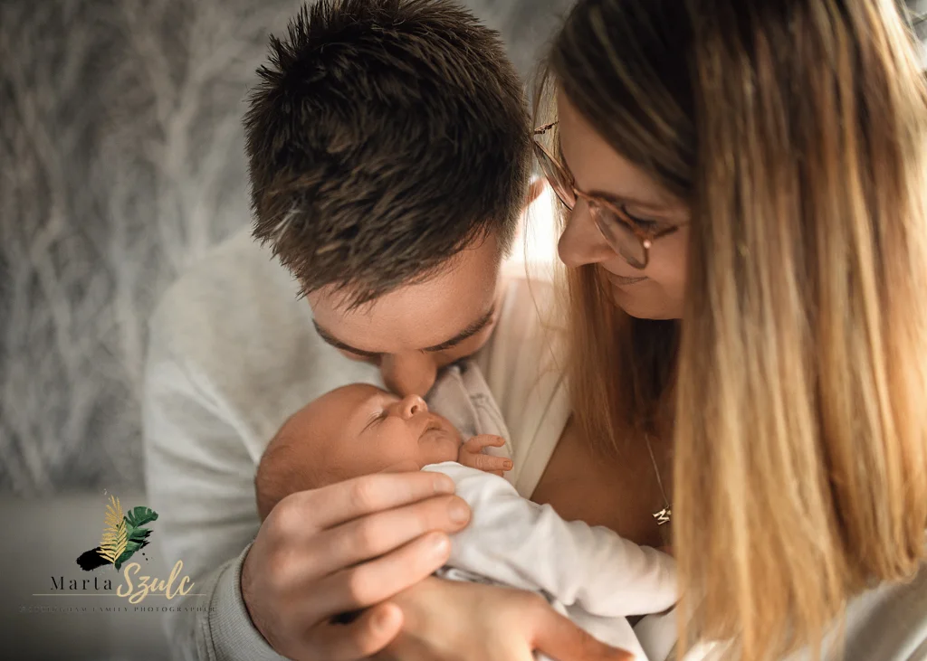 Parents cradling their newborn baby together in a heartfelt moment during a newborn photoshoot at home.